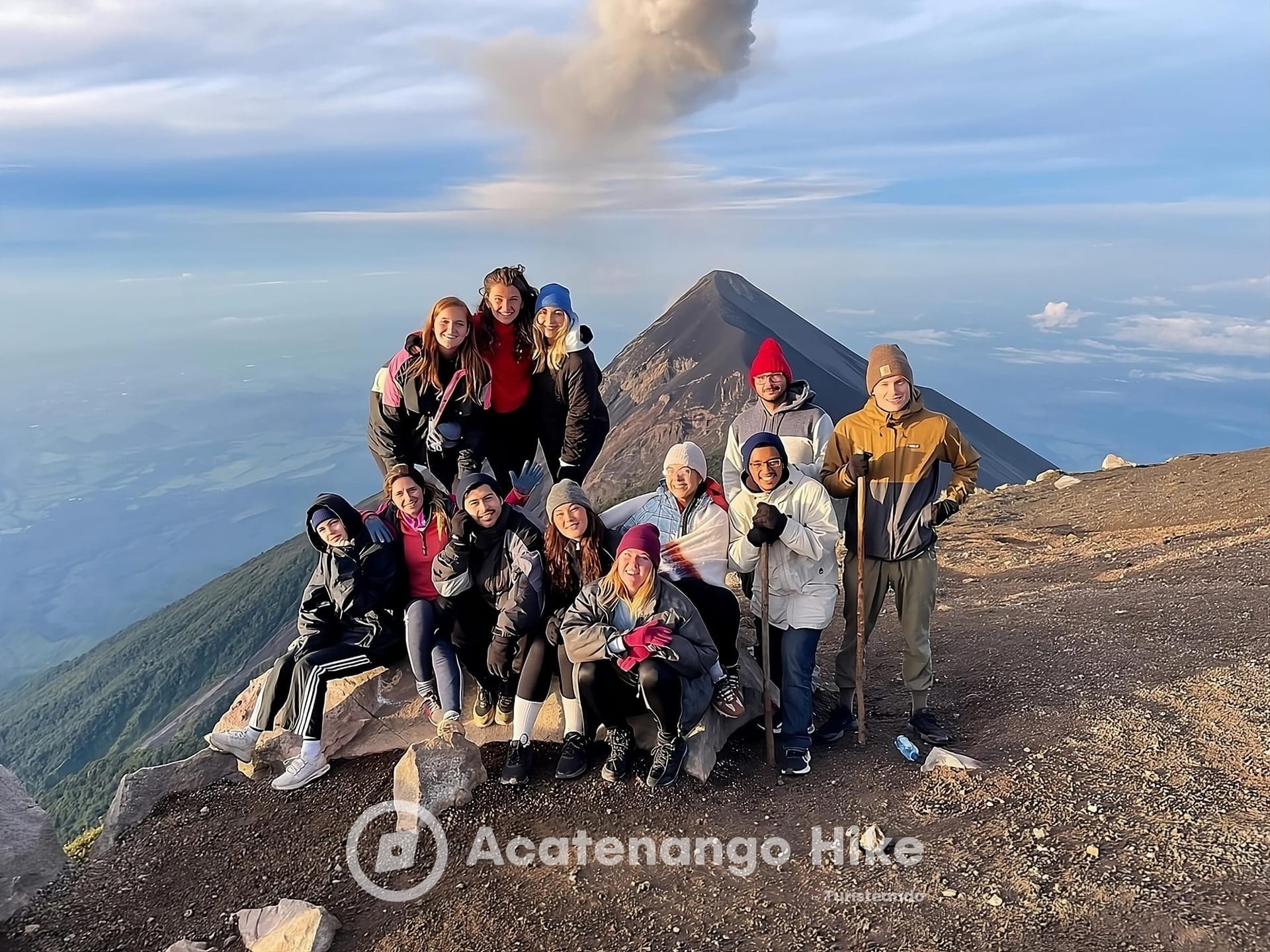 Foto de grupo no cume do Acatenango com o Fogo soltando fumaça
