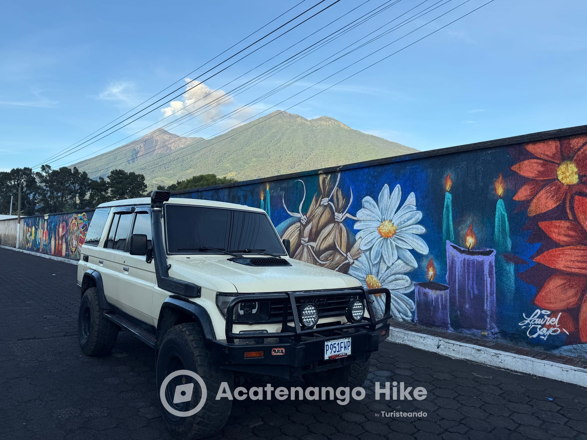 Toyota Land Cruiser 4x4 by a colorful mural below the volcanoes
