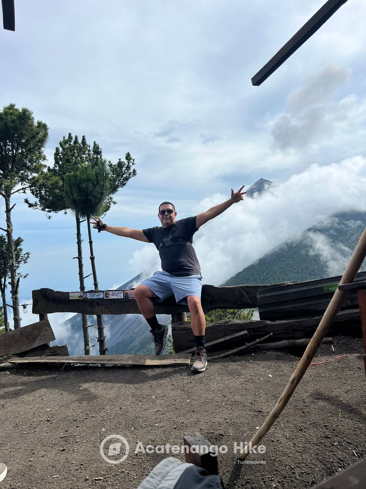 Excursionista en el mirador del campamento base con el Volcán de Fuego entre nubes