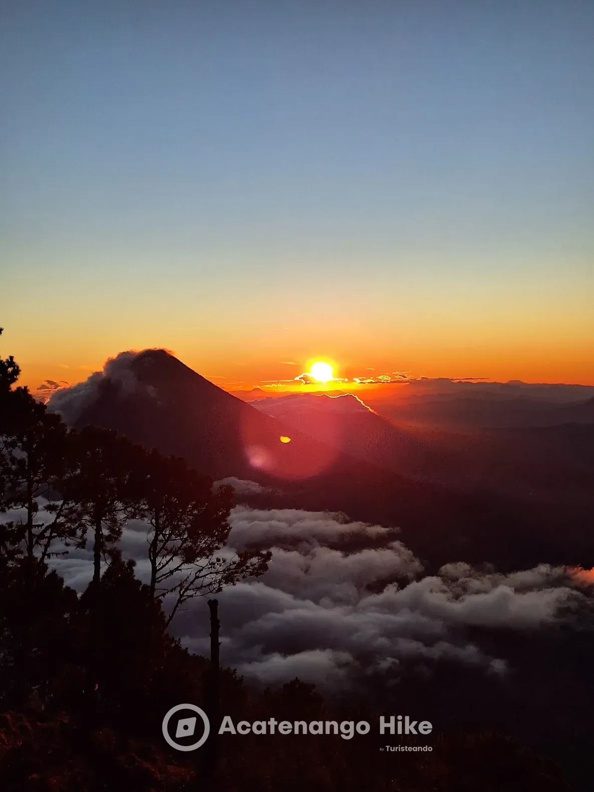 Sun rising behind Agua Volcano over a sea of clouds, seen from Acatenango