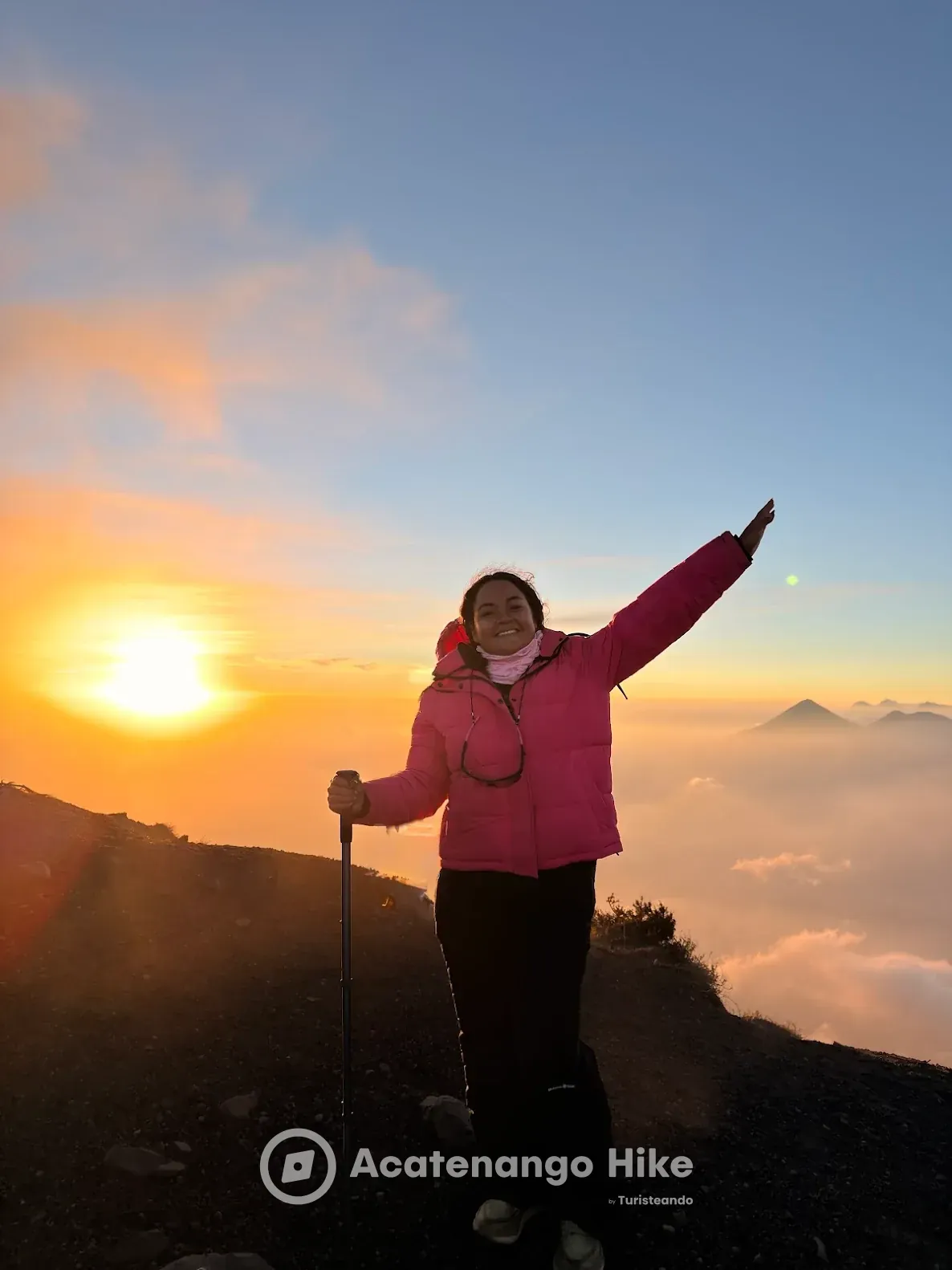 Hiker at the Acatenango summit at sunrise above a sea of clouds